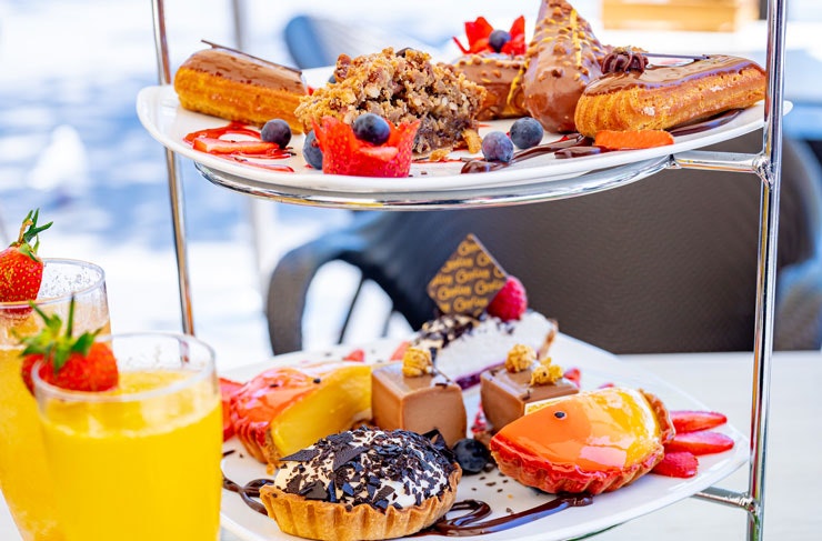 A cake stand filled with chocolate pastries and two mimosas.